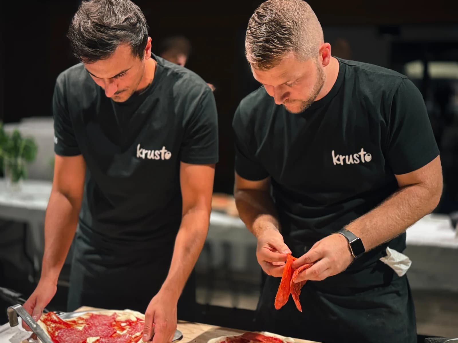 Zwei Menschen aus dem Krusto-Team bereiten gemeinsam Pizza beim Catering vor