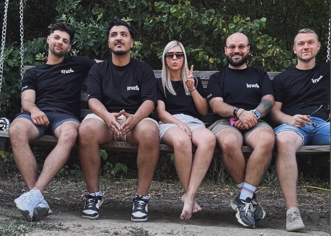 Fünf Menschen aus dem Krusto-Team sitzen gemeinsam auf einer Bank